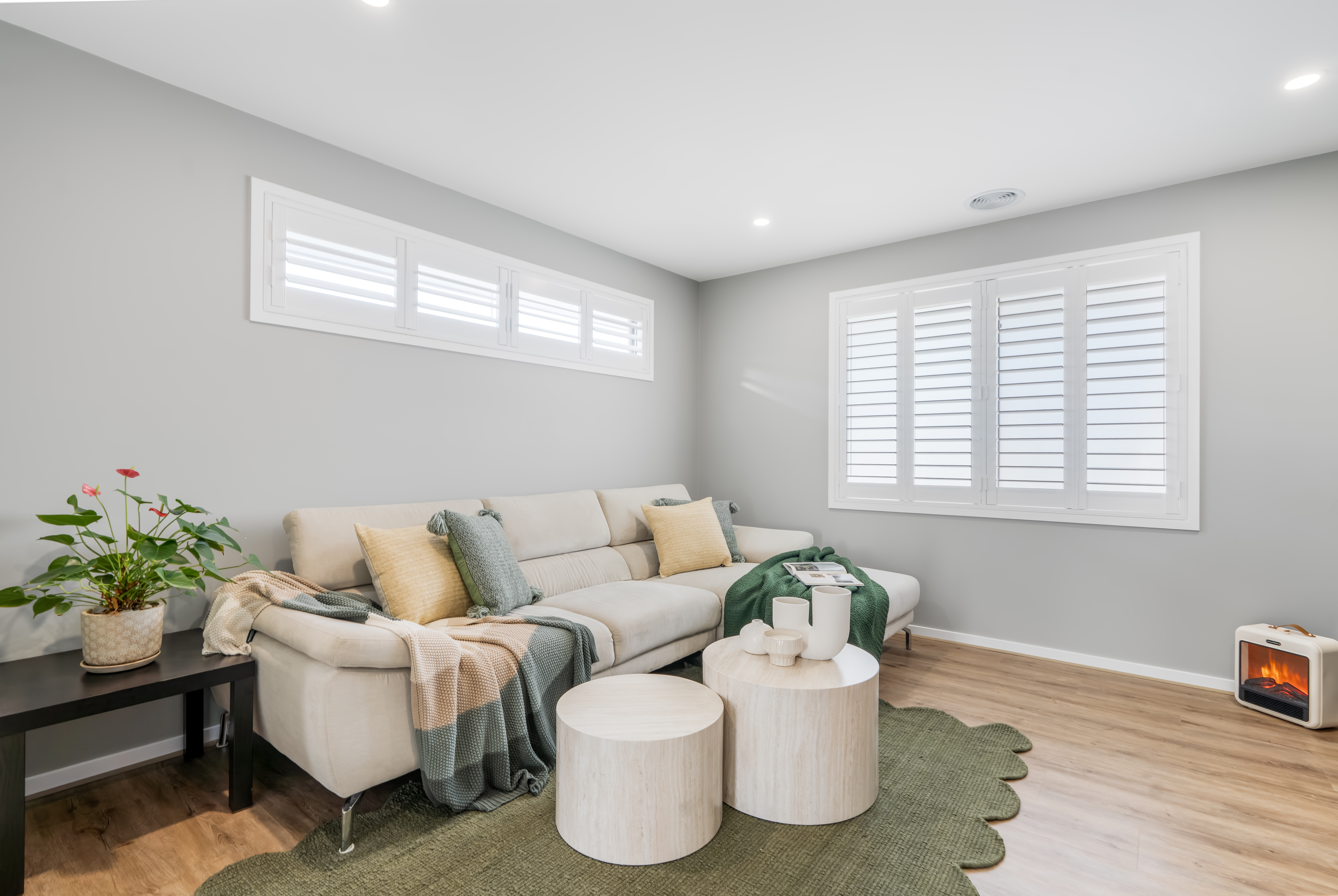 Light-filled staged living room with neutral palette and soft pink accents